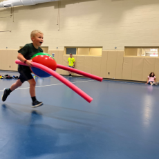 summer camp 2022 - boy playing game with pool noodles and beach ball