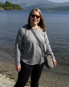 Judith standing in front of water on sand